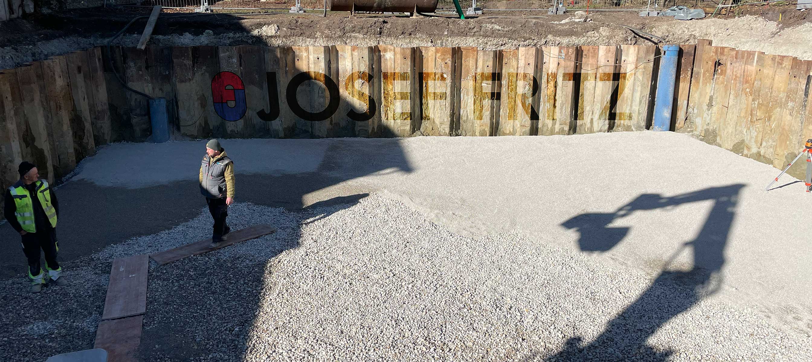 Ein Tieflader mit einem Mini-Bagger mit dem Fritz Tiefbau Logo.